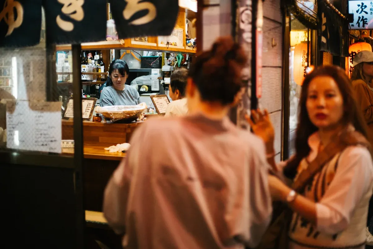 Lantern-lit alleyways of Omoide Yokocho in Shinjuku with yakitori smoke rising from authentic stalls during a Tokyo food tour